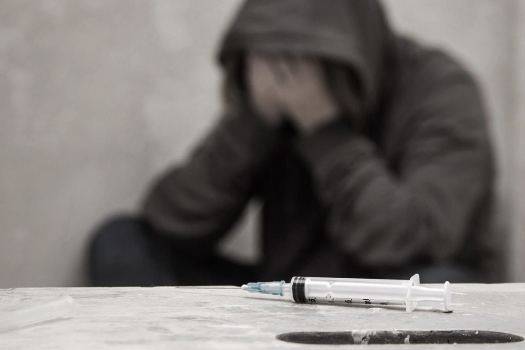a teen going through withdrawal while a needle sits on the table and he learns about teens and drug abuse