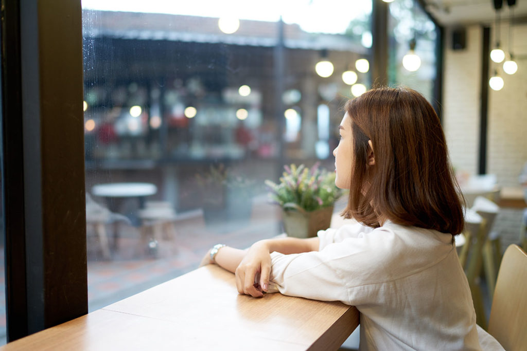 young woman staring out cafe window curious about different types of addiction