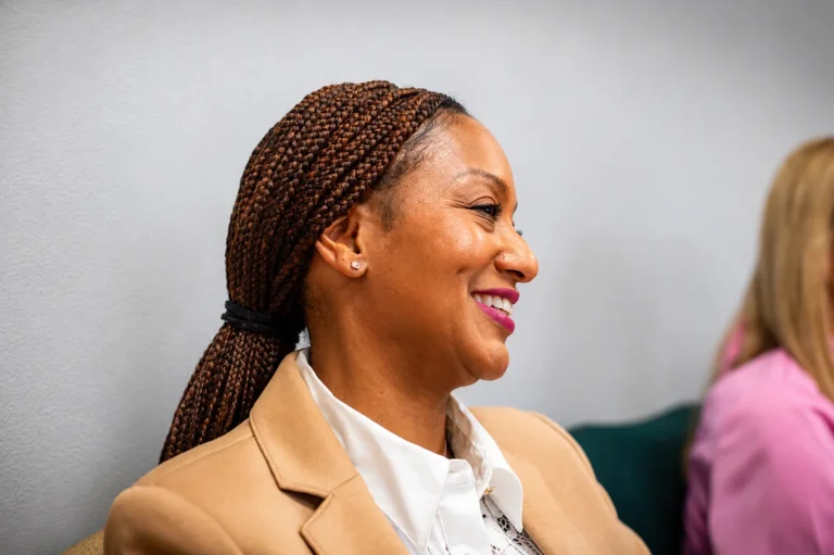 A woman smiling as she listens to someone speaking