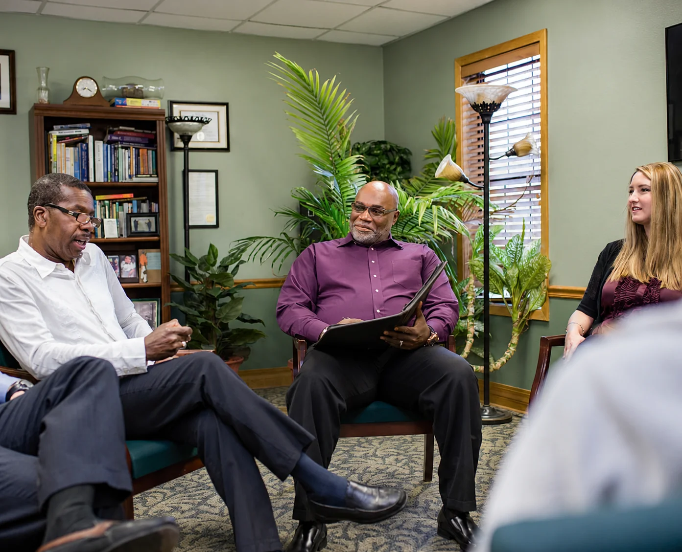 A group of patients and Palmetto staff talking and smiling in a group therapy session