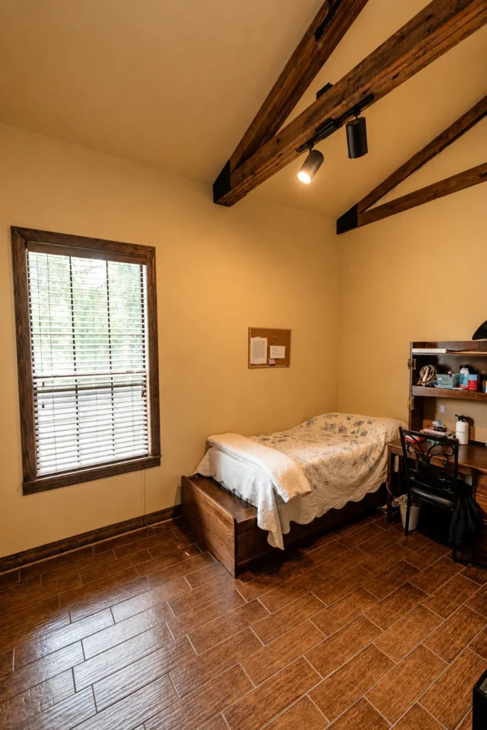 A spacious resident bedroom with a window, bed, and wood floors.